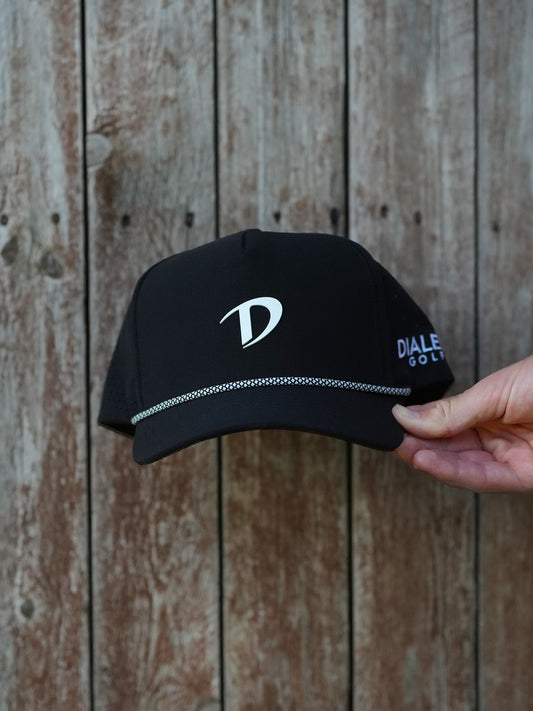 Black cap with a logo held by a hand against a wooden background