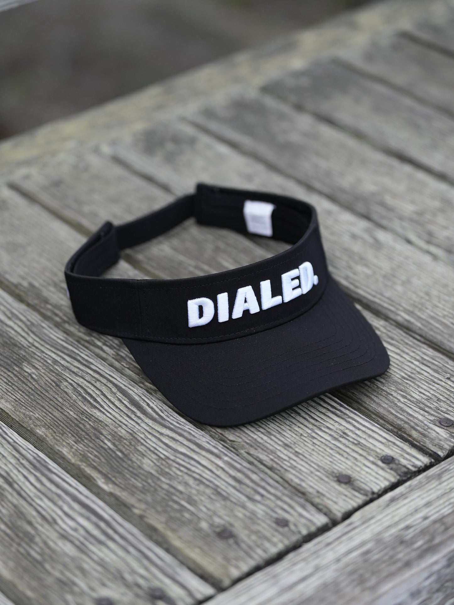 Black visor with 'DIALED' branding on a wooden surface