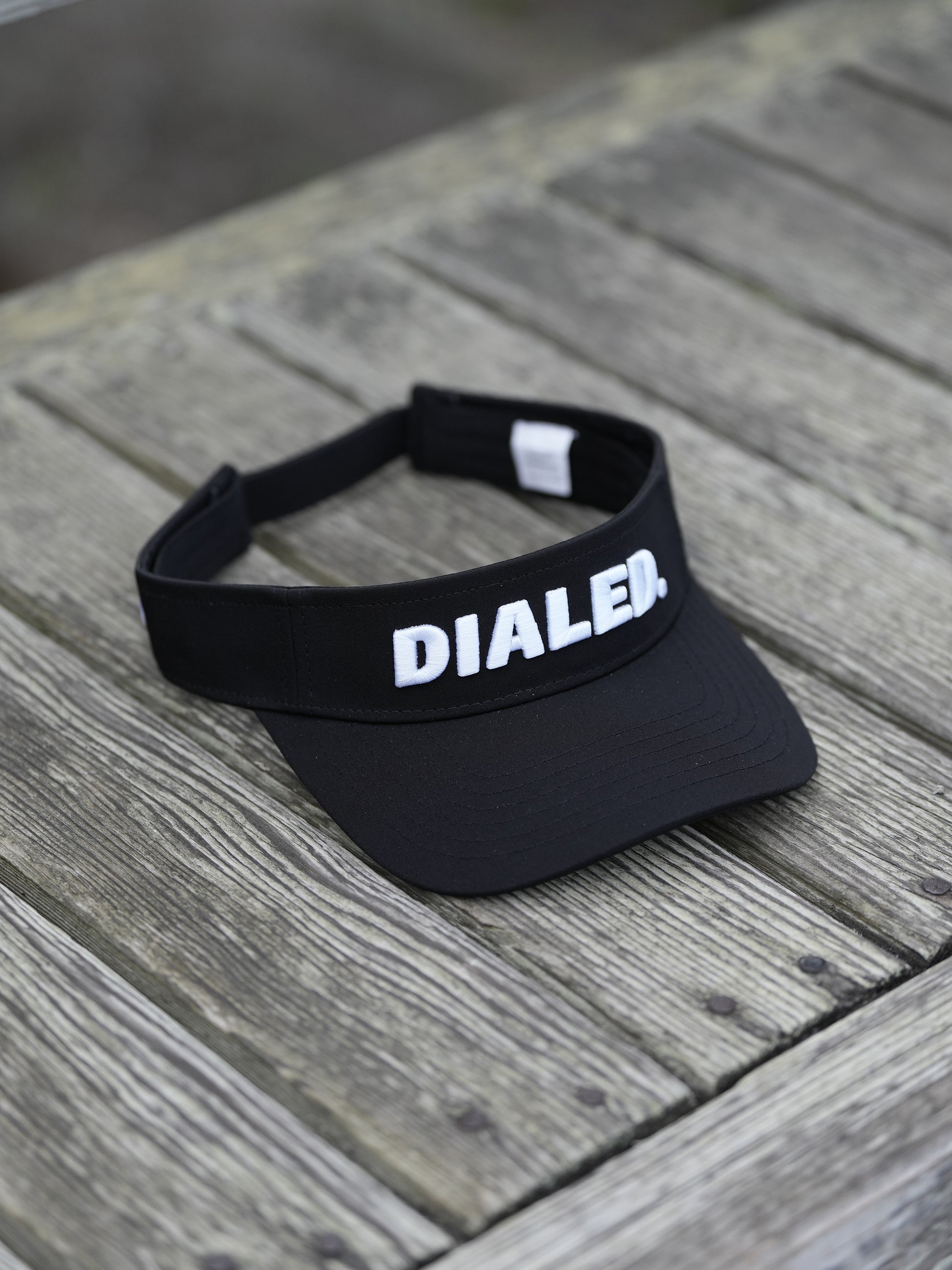 Black visor with 'DIALED' branding on a wooden surface