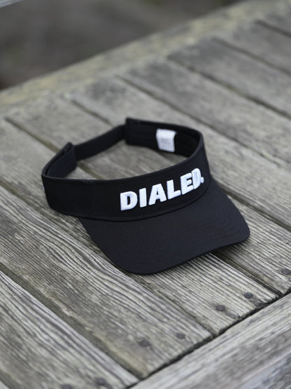 Black visor with 'DIALED' branding on a wooden surface