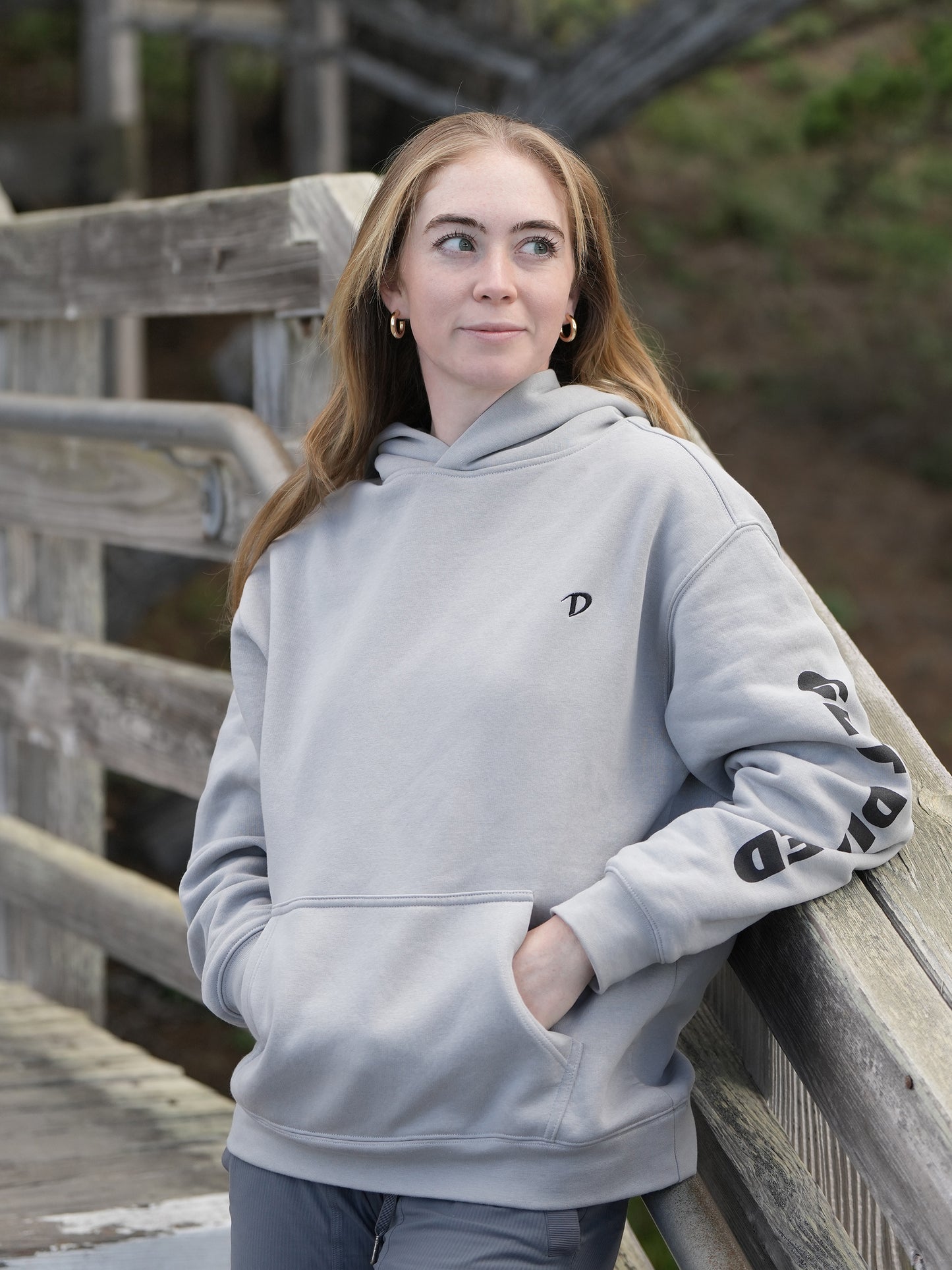 Grace Charis wearing The Storm grey-blue Dialed Golf hoodie with embroidered D logo and GET DIALED sleeve graphic